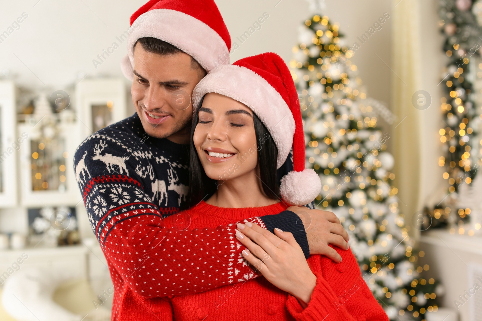 Photo of Happy couple in Santa hats at home. Christmas celebration