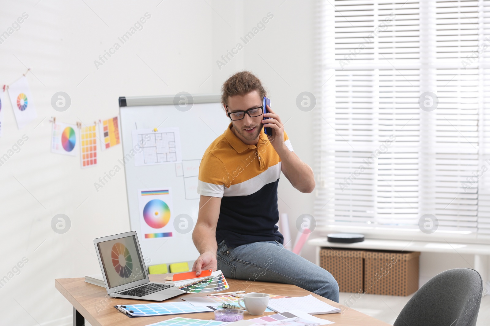 Photo of Interior designer talking on mobile phone in office