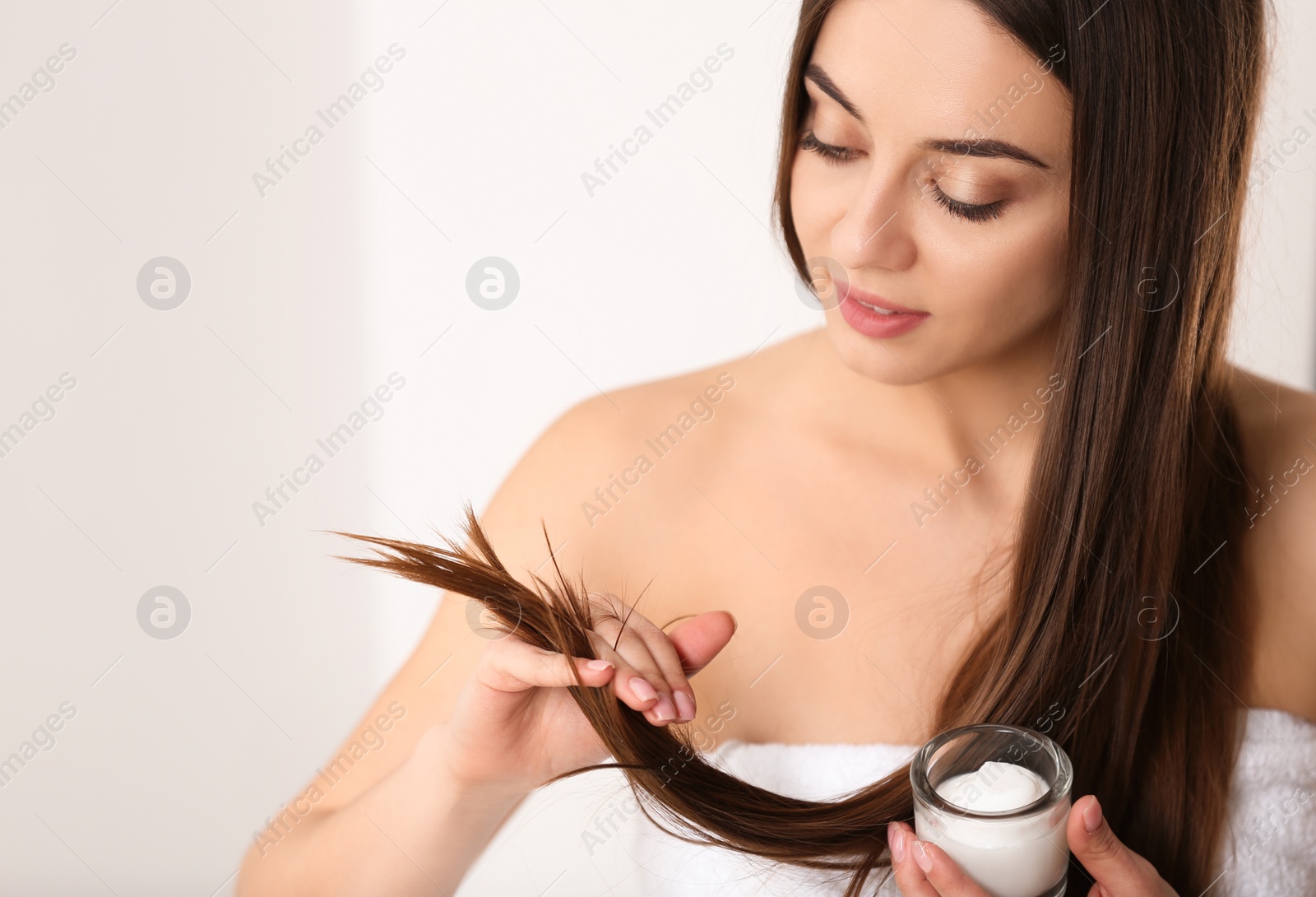 Photo of Woman with glass bowl of hair mask on light background. Space for text