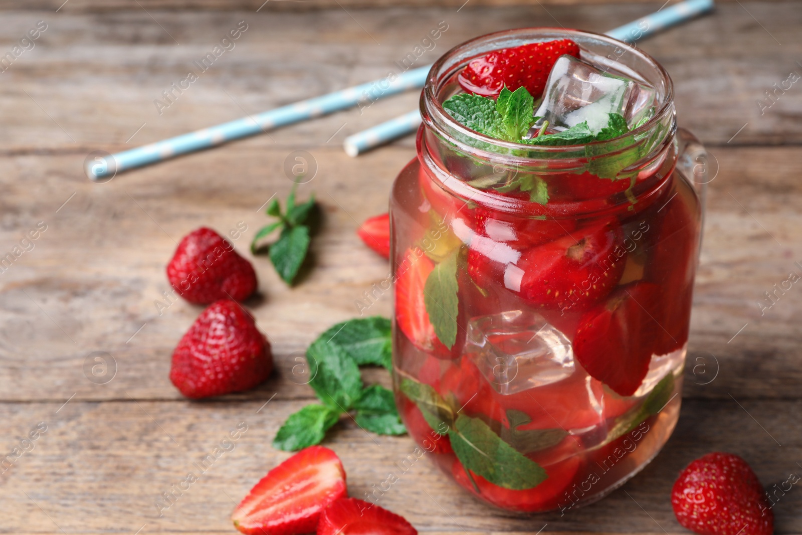 Photo of Mason jar of refreshing drink with strawberry and mint on wooden table, space for text