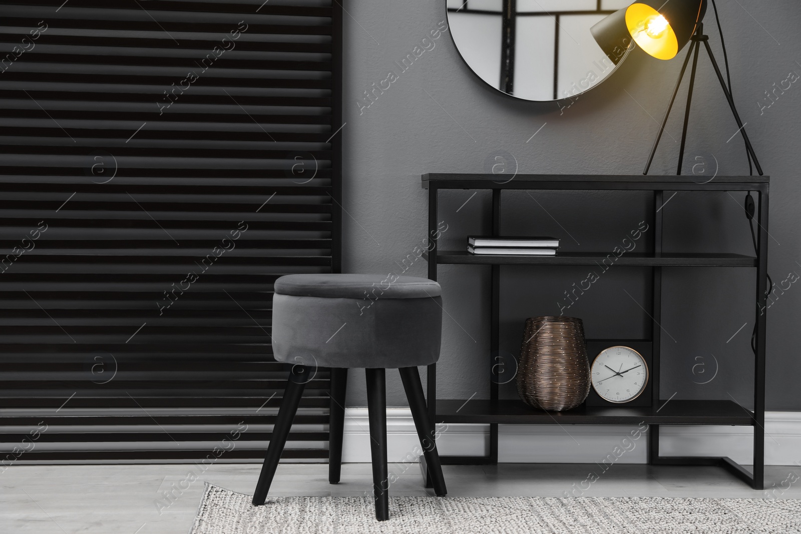 Photo of Console table with stool and mirror on grey wall in room. Interior design