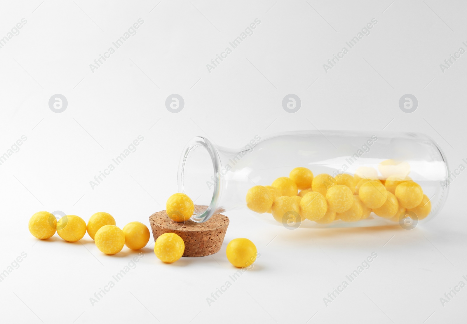 Photo of Tasty lemon drops and bottle on white background