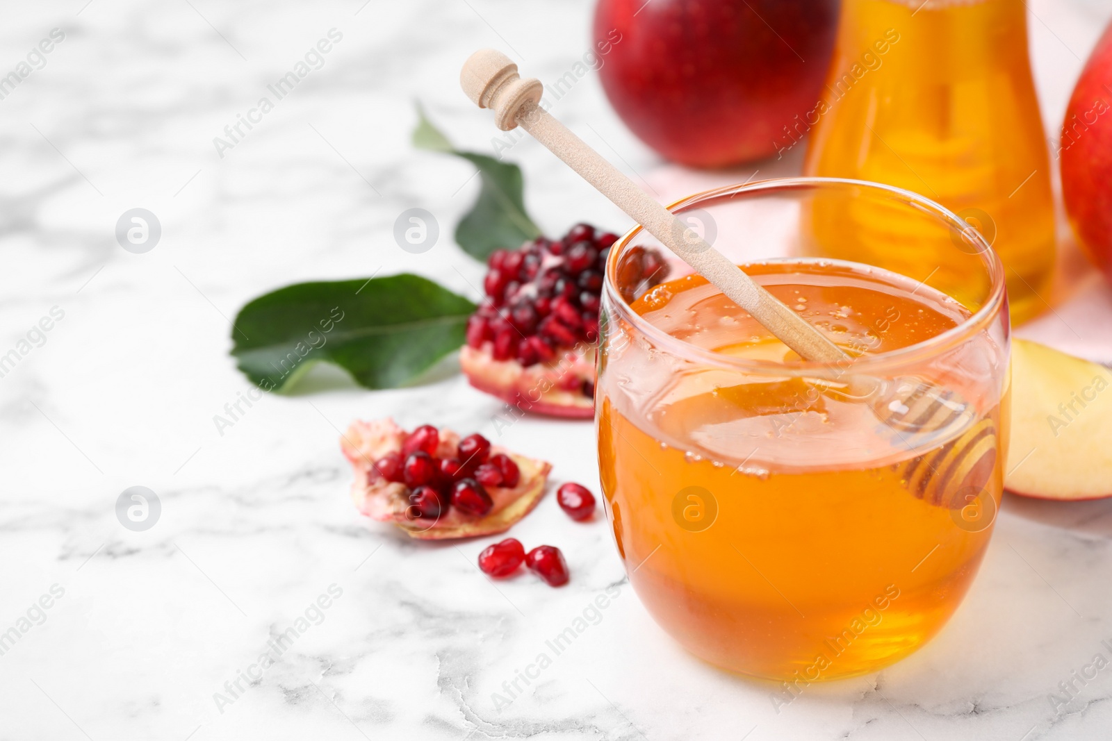 Photo of Honey, apples and pomegranate on white marble table. Rosh Hashanah holiday