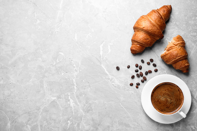 Photo of Tasty fresh croissants and coffee on light grey marble table, flat lay. Space for text