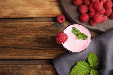 Photo of Glass of tasty raspberry smoothie on wooden table, flat lay. Space for text