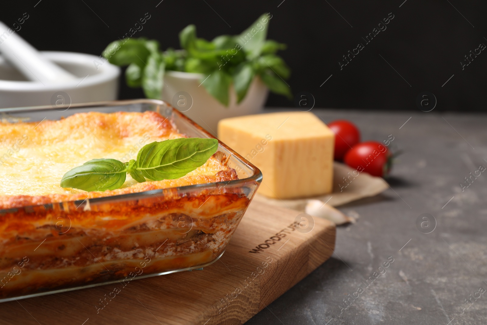 Photo of Tasty cooked lasagna in baking dish on grey table, closeup