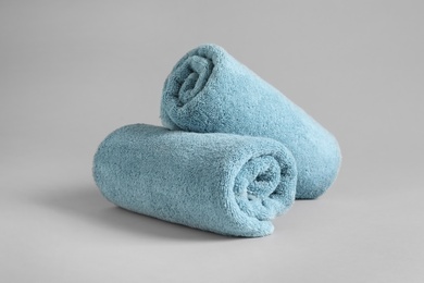 Fresh fluffy rolled towels on grey background