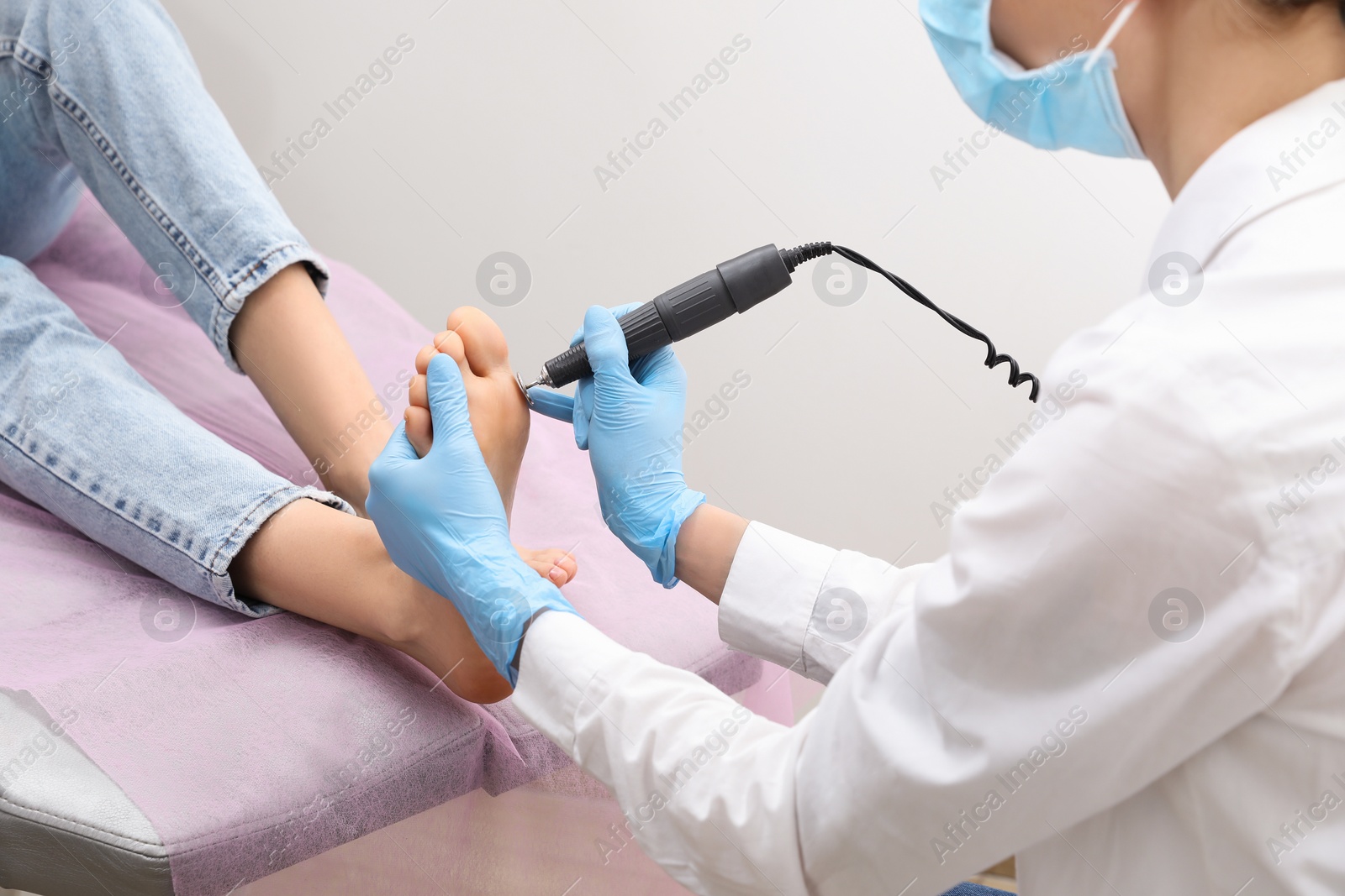 Photo of Professional master making hardware pedicure for client in beauty salon, closeup