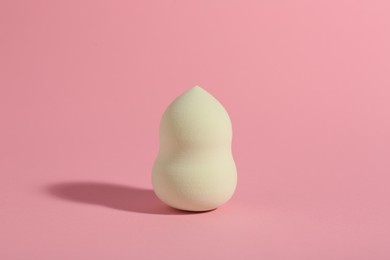 Photo of One white makeup sponge on pink background