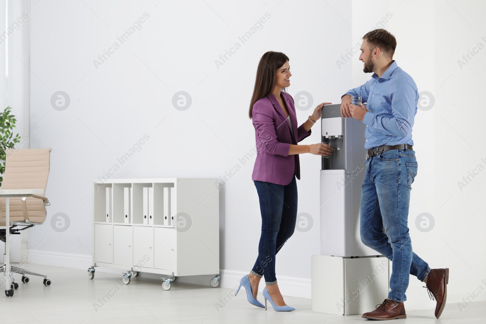 Photo of Employees having break near water cooler in office. Space for text