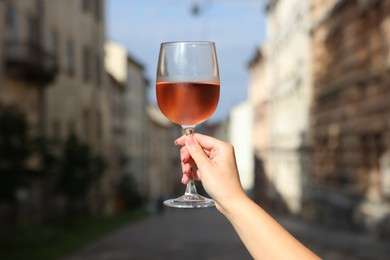 Photo of Woman holding glass of rose wine outdoors, closeup