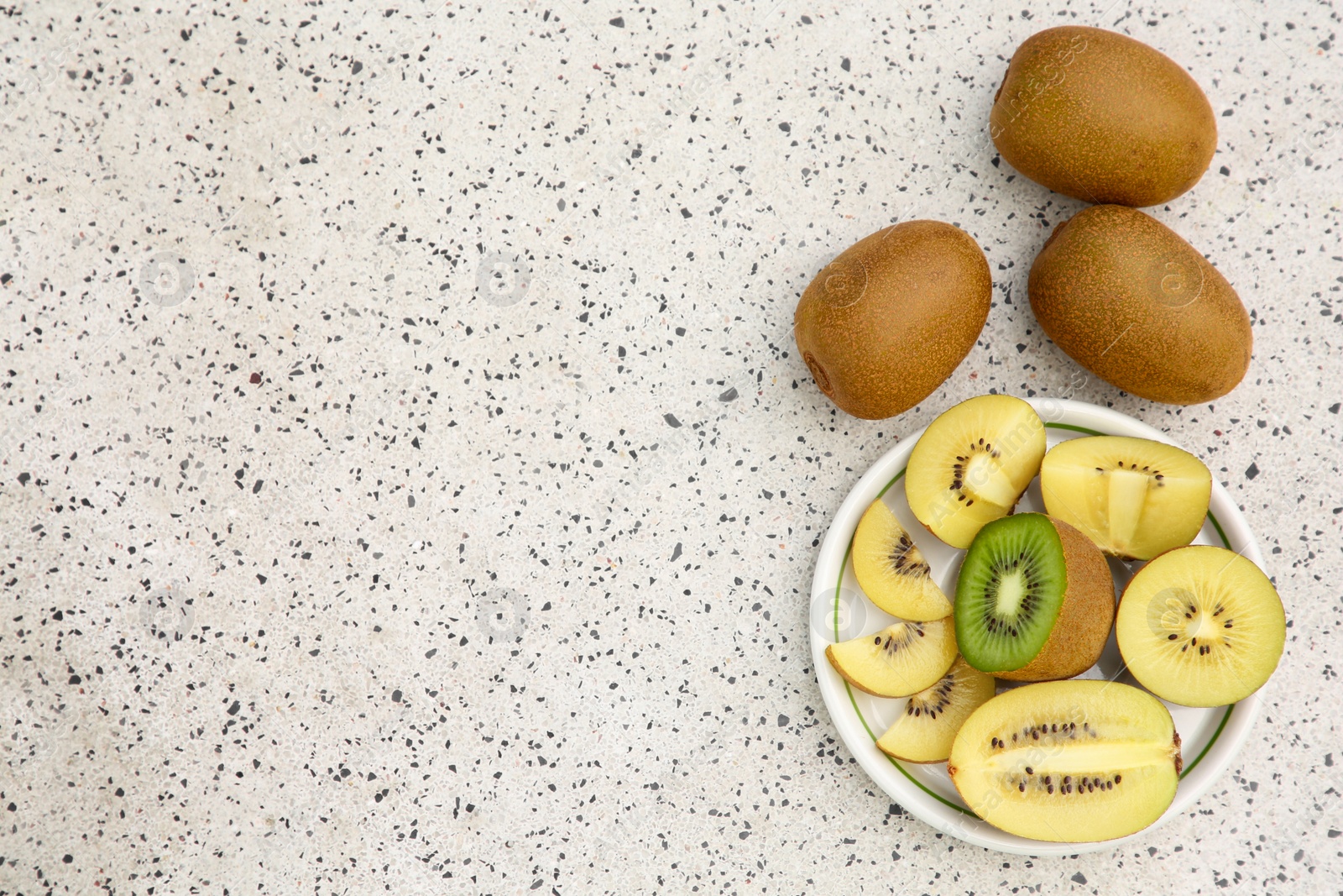 Photo of Whole and cut fresh kiwis on white table with pattern, flat lay. Space for text