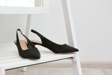 Photo of Pair of female shoes on floor mirror shelf indoors