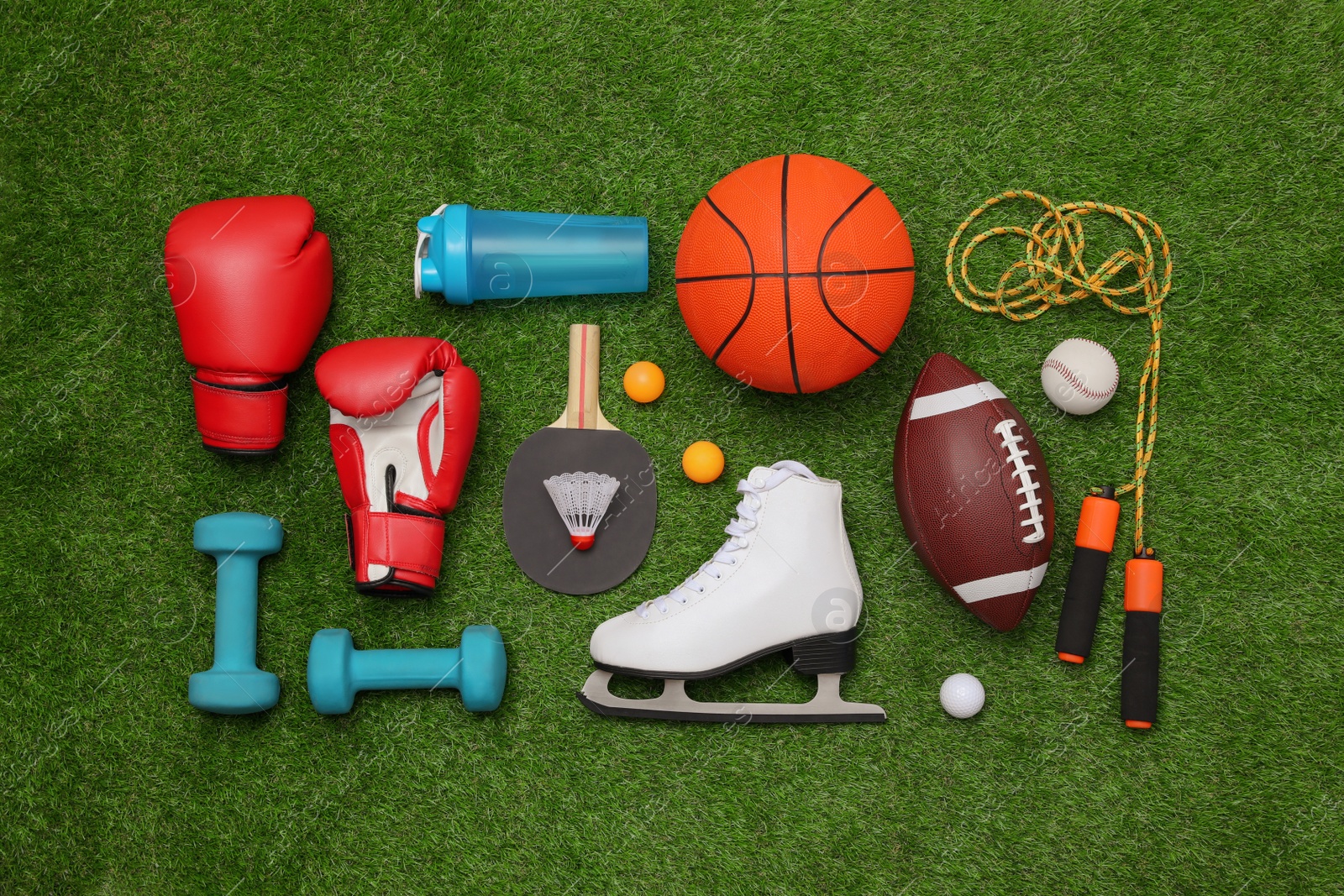 Photo of Different sport equipment on green grass, flat lay