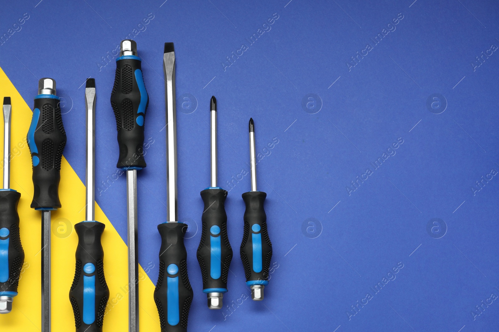 Photo of Set of screwdrivers on color background, flat lay. Space for text