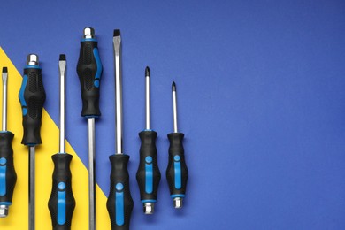 Set of screwdrivers on color background, flat lay. Space for text