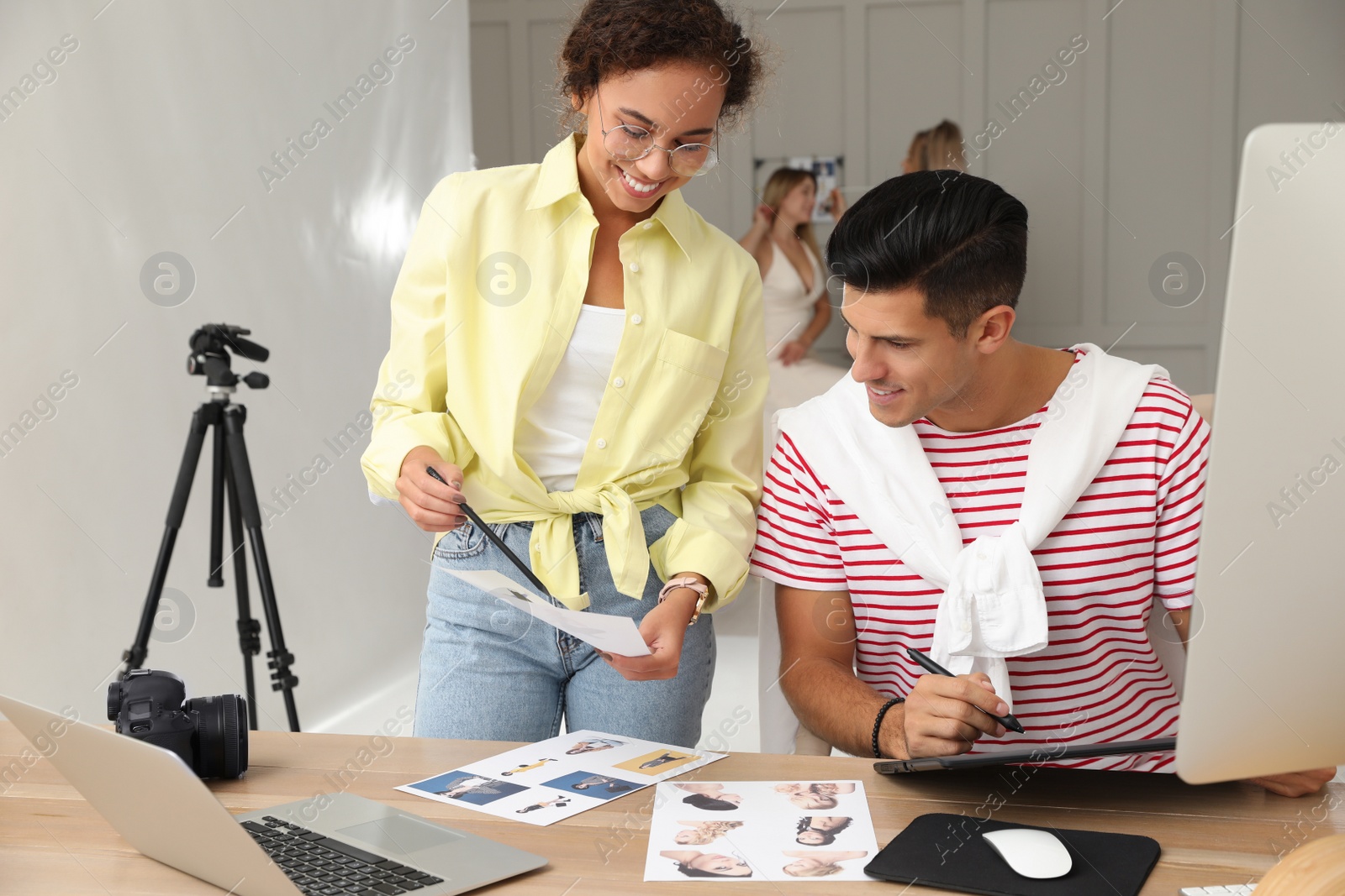 Photo of Professional retoucher with colleague working at desk in photo studio