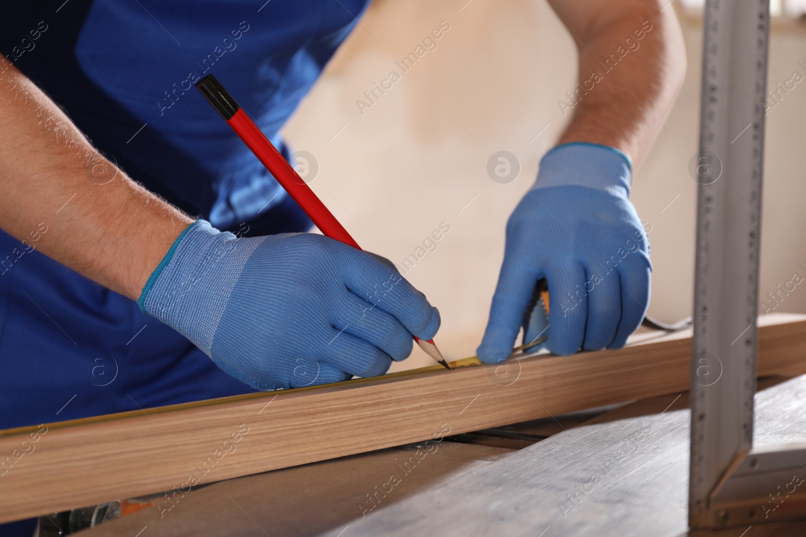 Photo of Professional carpenter making mark on wooden bar in workshop, closeup