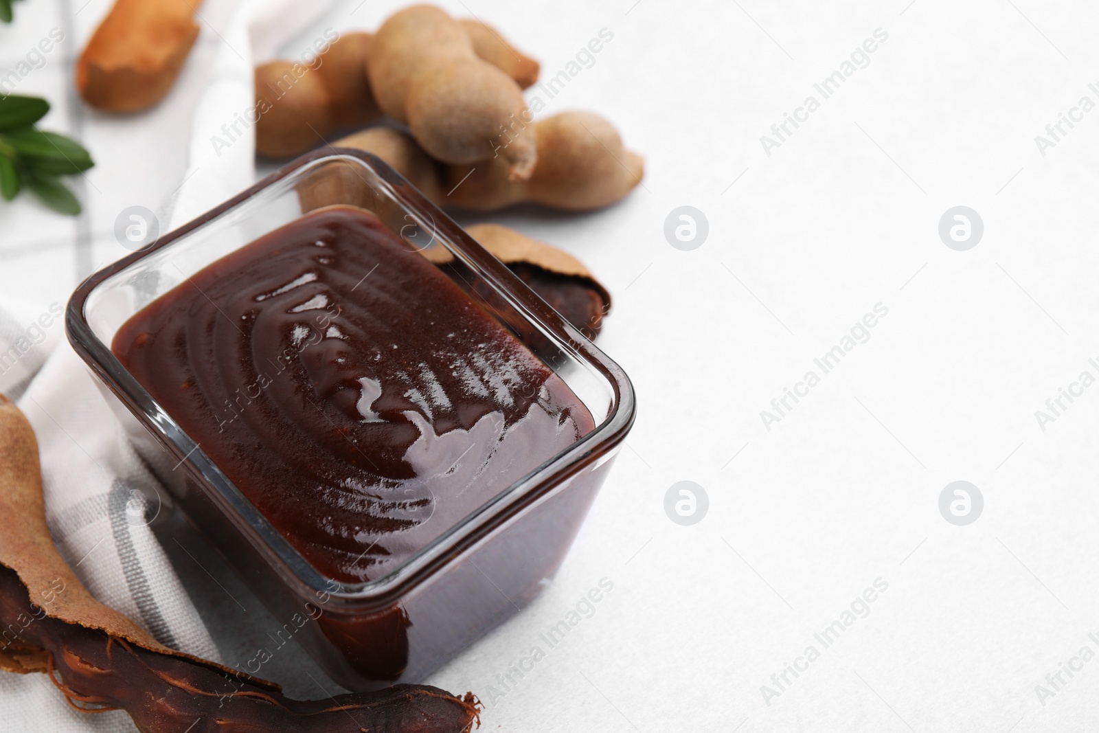 Bowl of tasty tamarind sauce and fresh pods on light table. Space for text Photo of Bowl of tasty tamarind sauce and fresh pods on light table. Space for text