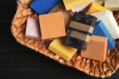 Many different handmade soap bars in wicker basket on table, top view