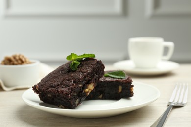 Photo of Delicious brownies with nuts and mint on white wooden table