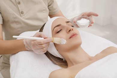 Young woman during face peeling procedure in salon