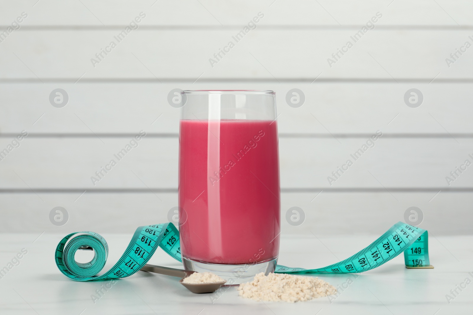 Photo of Tasty shake, measuring tape and powder on white table. Weight loss