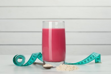 Photo of Tasty shake, measuring tape and powder on white table. Weight loss