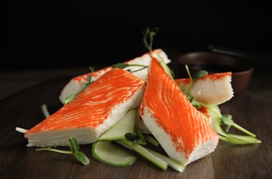 Photo of Fresh crab sticks with cucumber and soy sauce on serving board, closeup