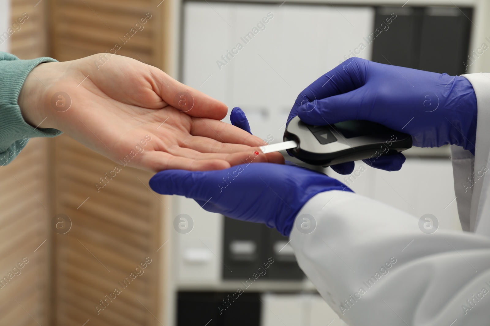 Photo of Diabetes. Doctor checking patient's blood sugar level with glucometer in clinic, closeup