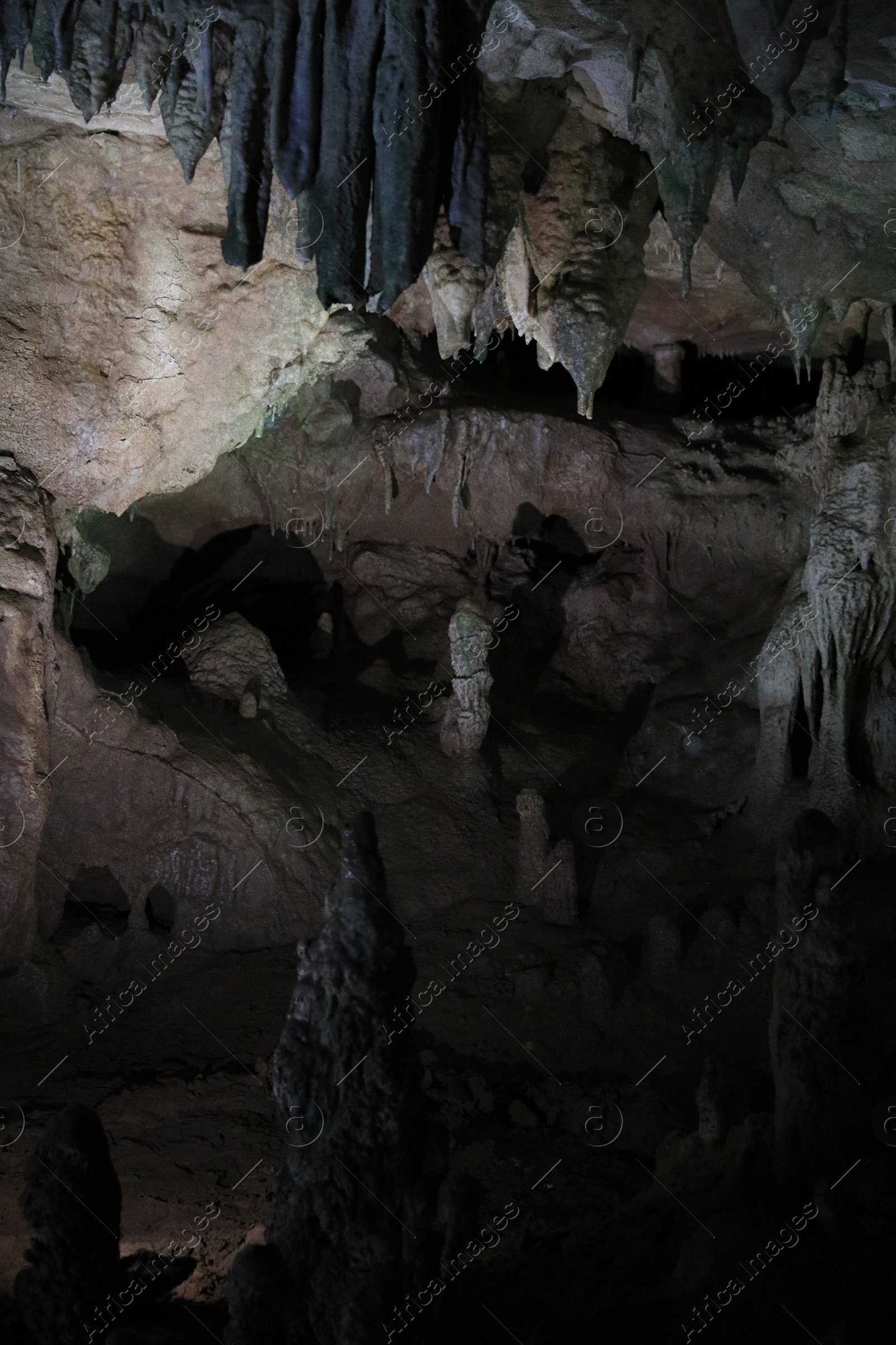 Photo of Picturesque view of many stalactite and stalagmite formations in dark cave