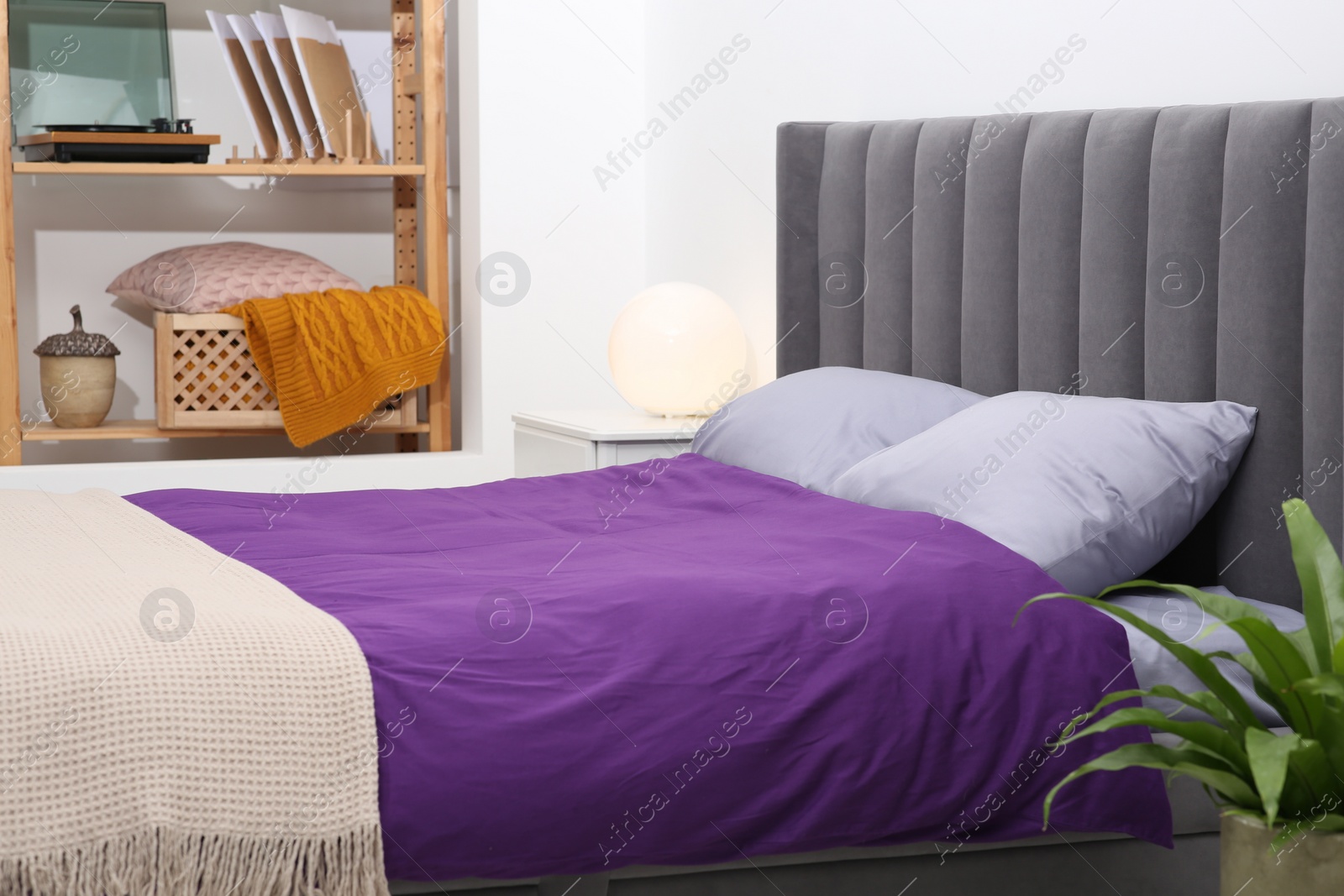 Photo of Comfortable bed with purple linens in bedroom. Interior design