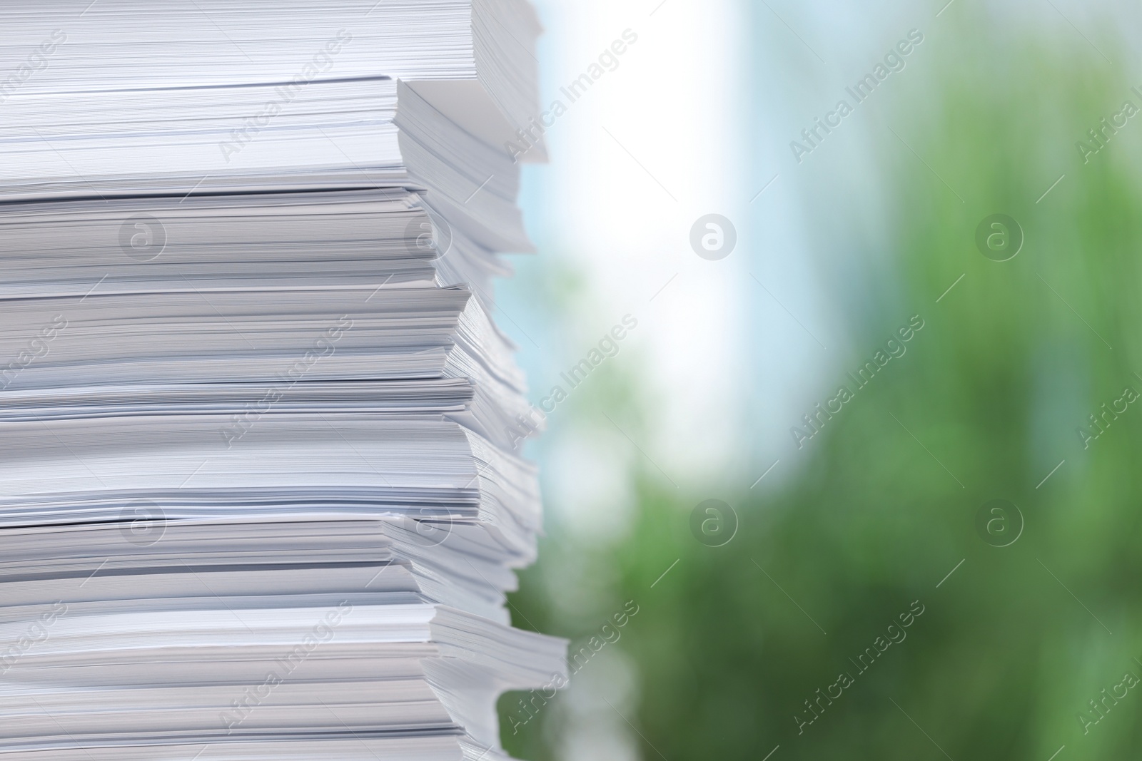 Photo of Stack of paper sheets against blurred background, closeup. Space for text