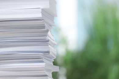 Photo of Stack of paper sheets against blurred background, closeup. Space for text