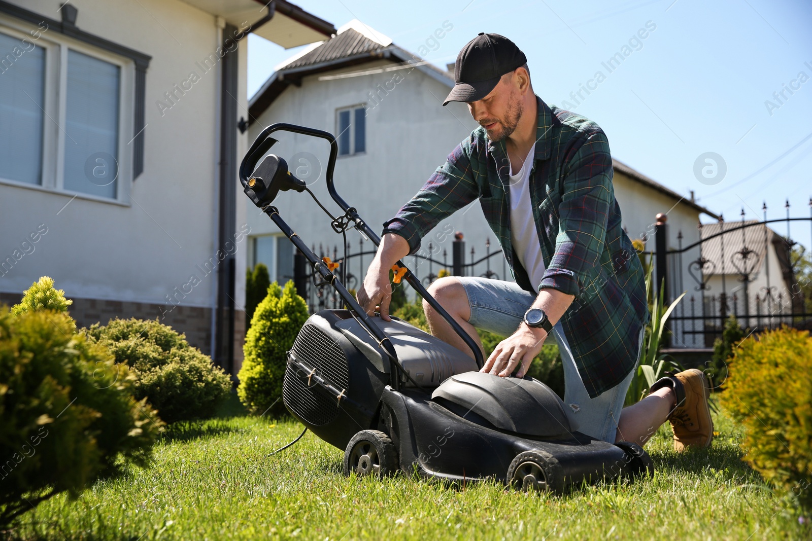 Photo of Man cutting green grass with lawn mower in garden