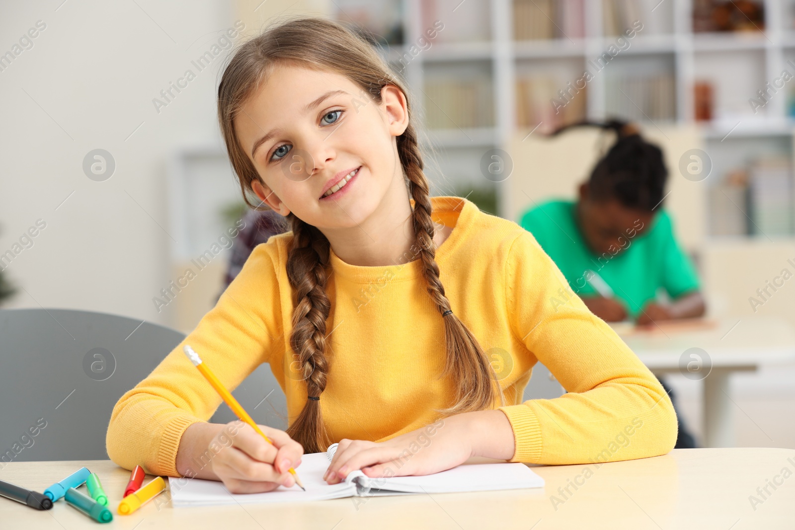 Photo of Portrait of smiling little girl studying in classroom at school