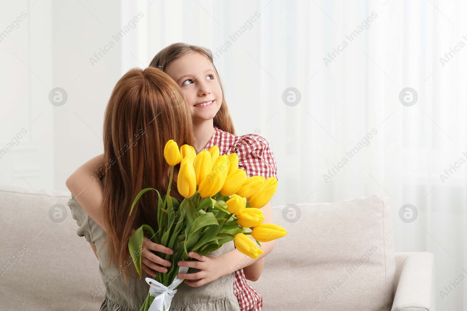 Photo of Daughter congratulating mom with bouquet of yellow tulips at home, space for text