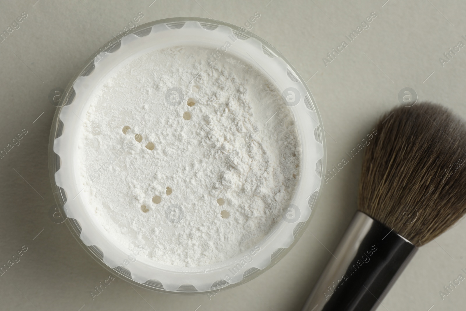 Photo of Rice loose face powder and makeup brush on light grey background, flat lay