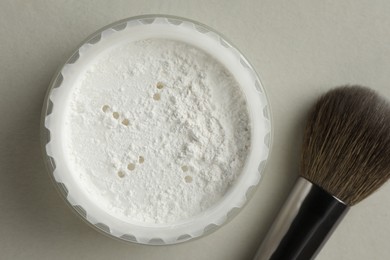 Photo of Rice loose face powder and makeup brush on light grey background, flat lay