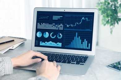 Woman using laptop at desk in office, closeup. Fintech concept