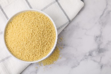 Raw couscous in bowl on light table, top view. Space for text