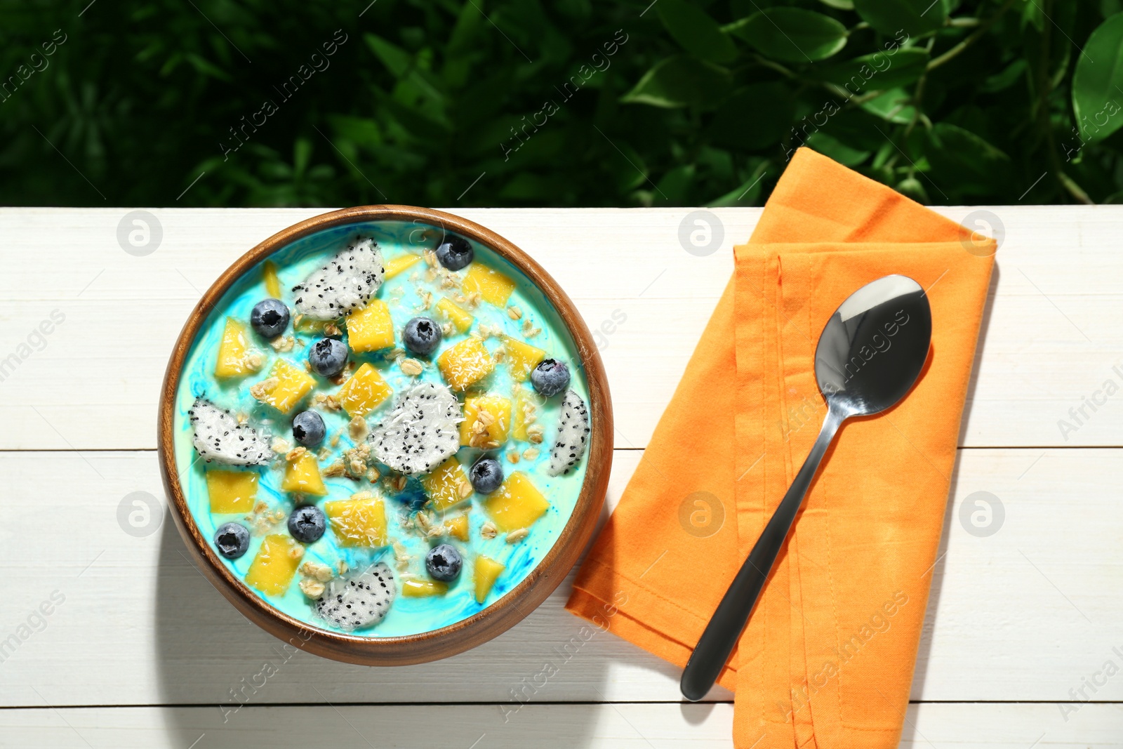 Photo of Delicious smoothie bowl with fresh fruits, blueberries and oatmeal served on white wooden table outdoors, flat lay