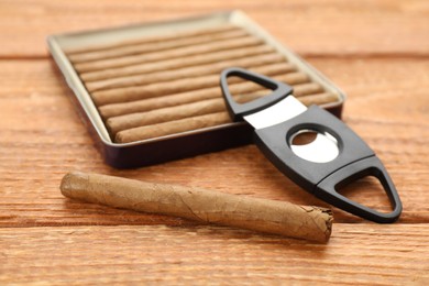 Photo of Cigars and guillotine cutter on wooden table