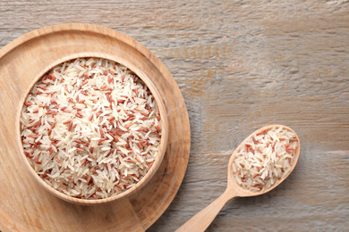 Photo of Mix of brown and polished rice on wooden table, flat lay