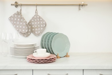 Clean plates, glasses and cup on white marble countertop in kitchen, space for text