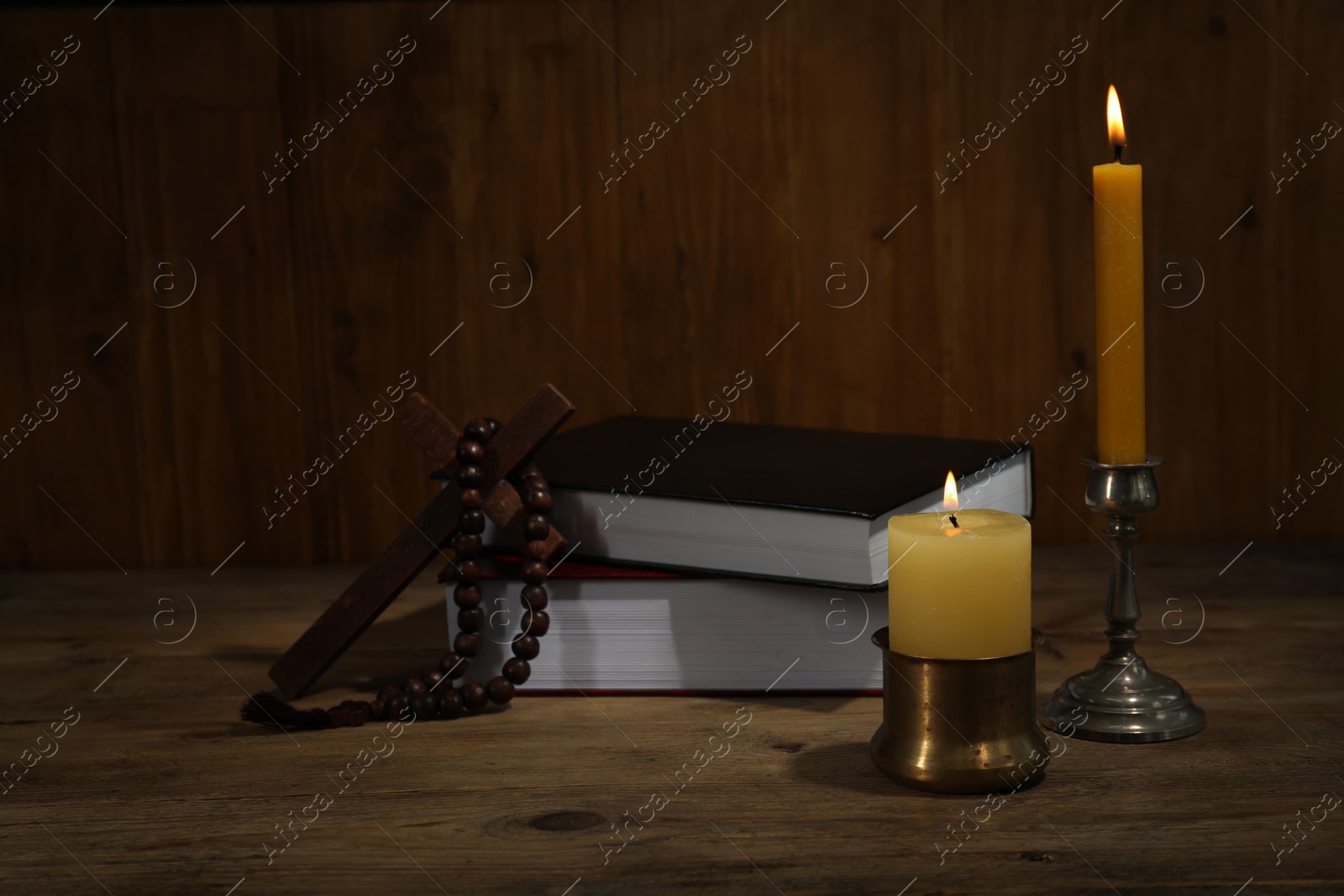 Photo of Church candles, Bible, cross and rosary beads on wooden table