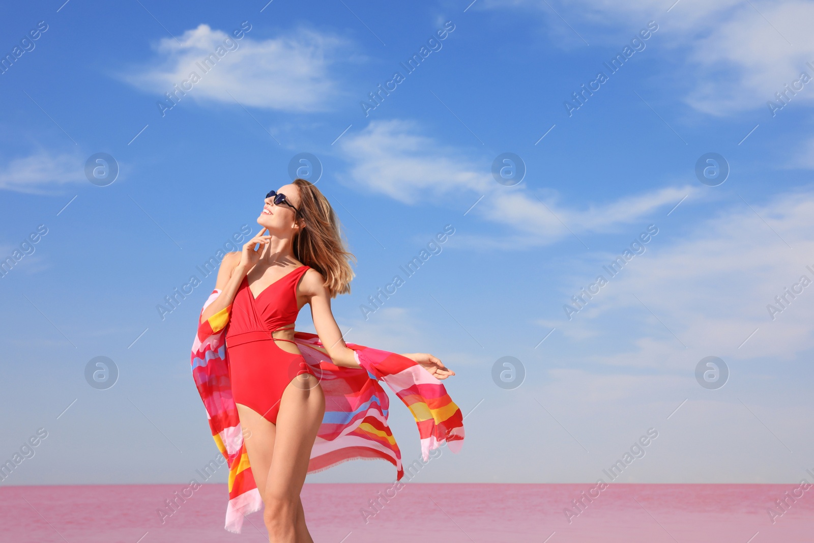 Photo of Beautiful woman in swimsuit posing near pink lake on sunny day