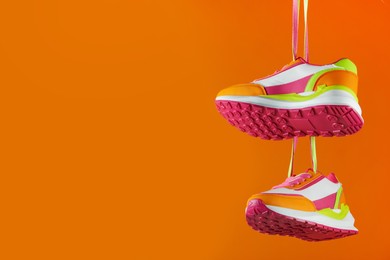 Photo of Pair of stylish sneakers on orange background. Space for text