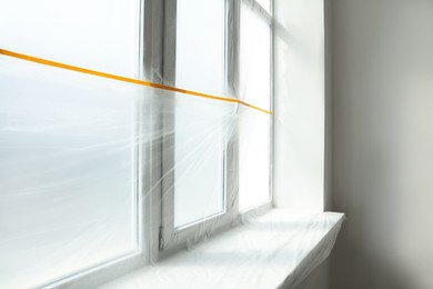 Photo of Window and sill covered by plastic film indoors