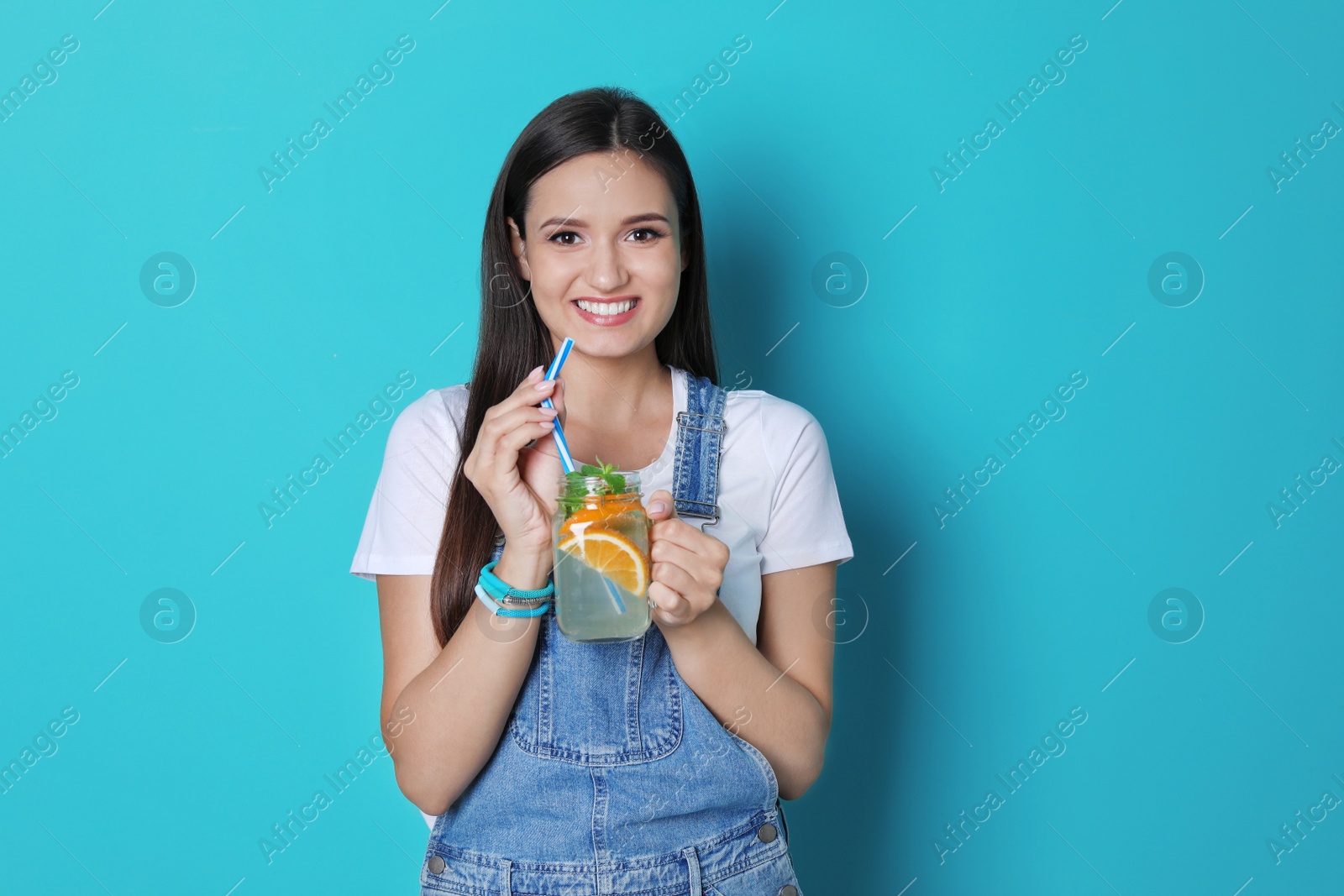 Photo of Young woman with mason jar of tasty lemonade on color background. Natural detox drink